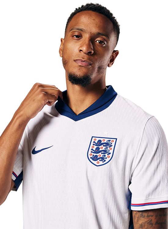 Person wearing a white sports jersey with a logo, on a plain background