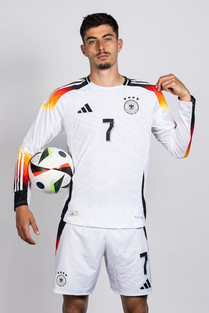 Person wearing a white soccer jersey with black and orange accents, holding a soccer ball.