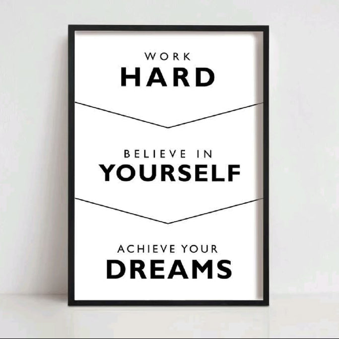A framed motivational poster with black text on a white background, reading 'WORK HARD BELIEVE IN YOURSELF ACHIEVE YOUR DREAMS,' shown leaning against a light wall. The name 'OZIL KHAN' appears above the frame.